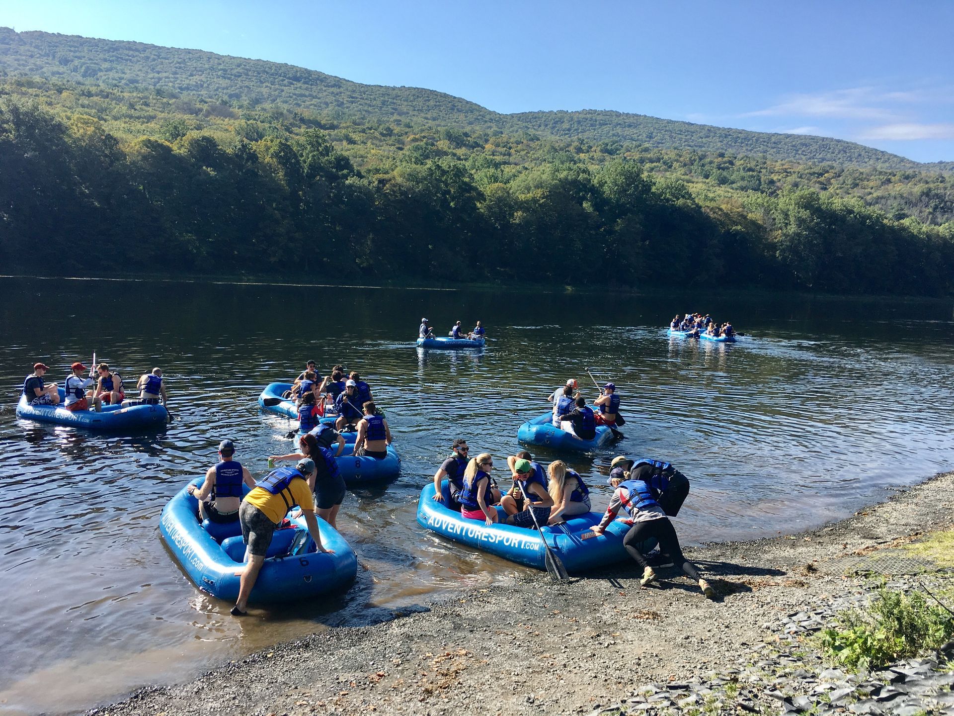 A group of people are rowing adventure sports rafts on a lake.