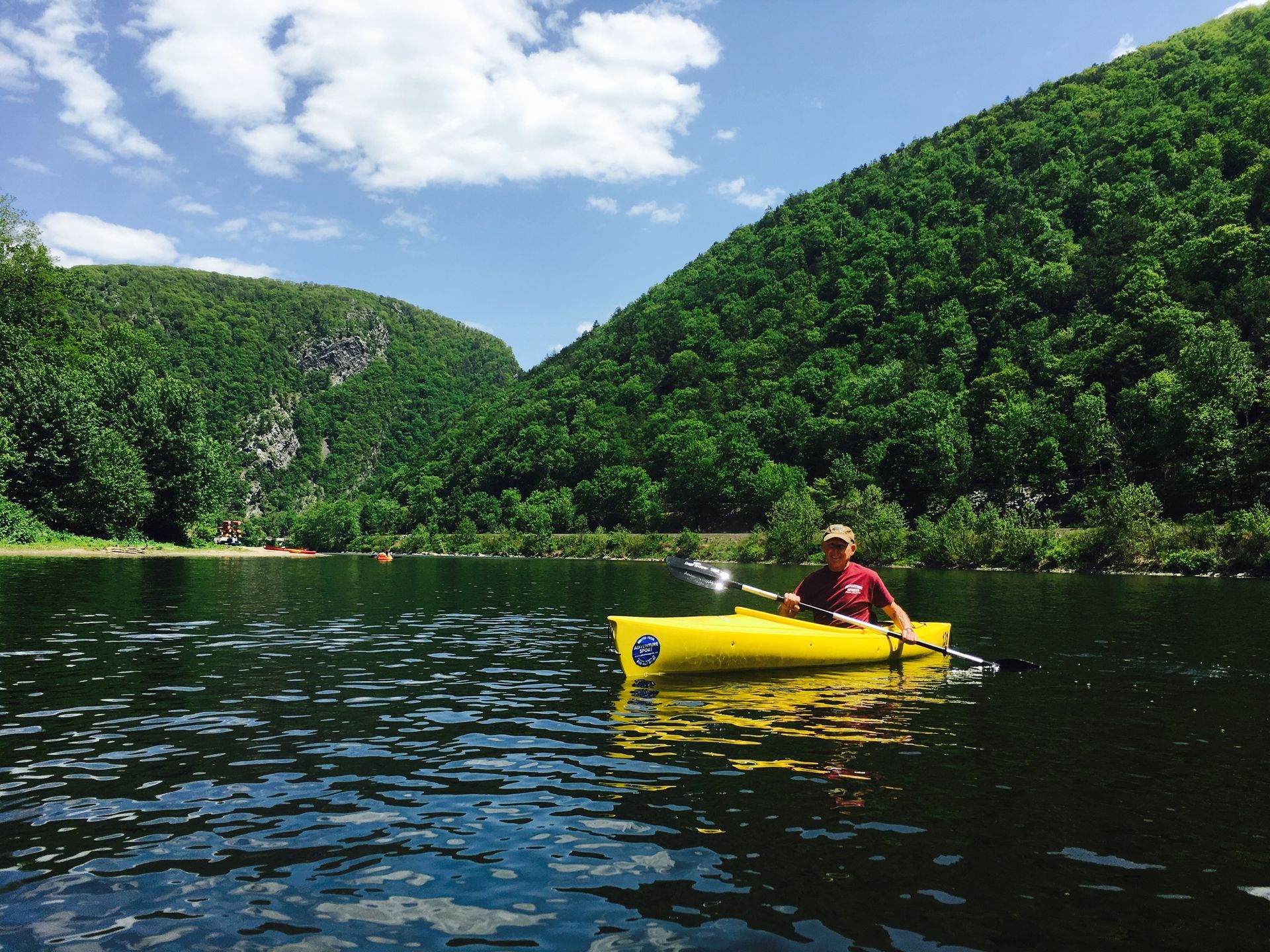 A man is paddling a yellow adventure sports kayak on a lake
