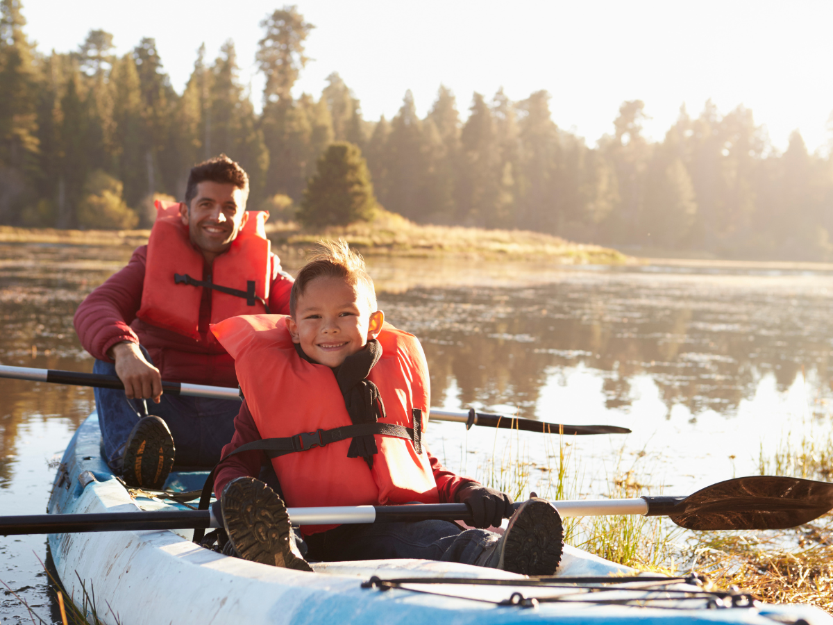 A man and a child are in a kayak on a lake. A man and a child are in a kayak on a lake.