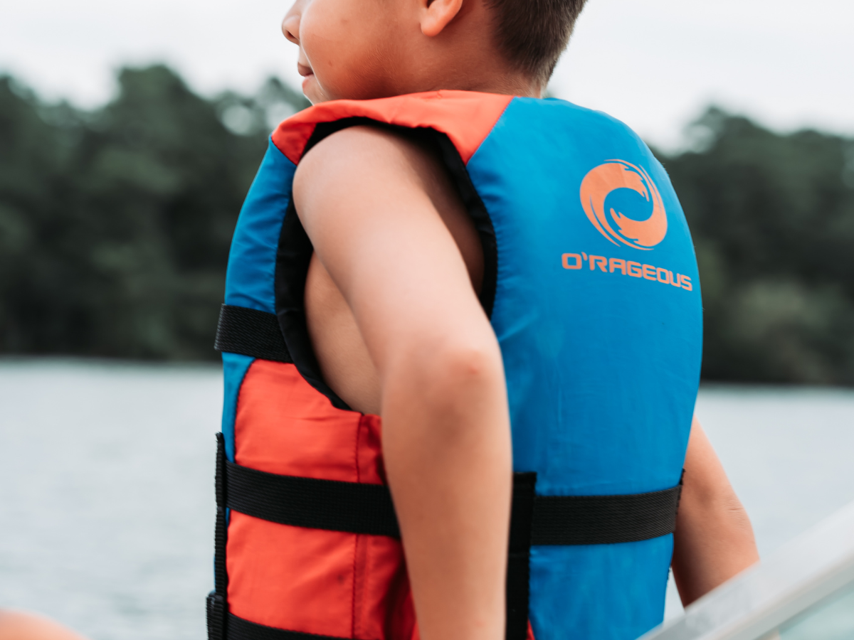 A young boy wearing a life jacket is sitting on a boat.