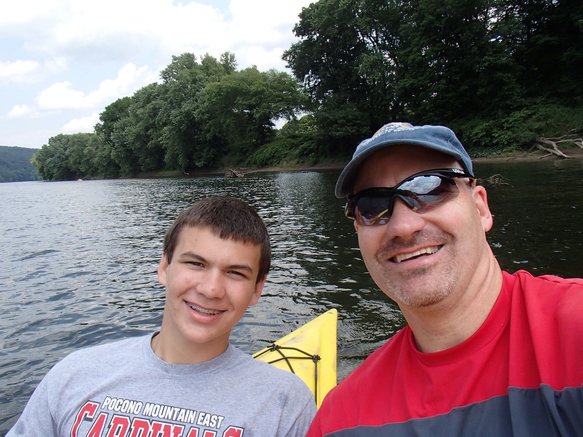 A man and a boy at adventure sports are posing for a picture in the water