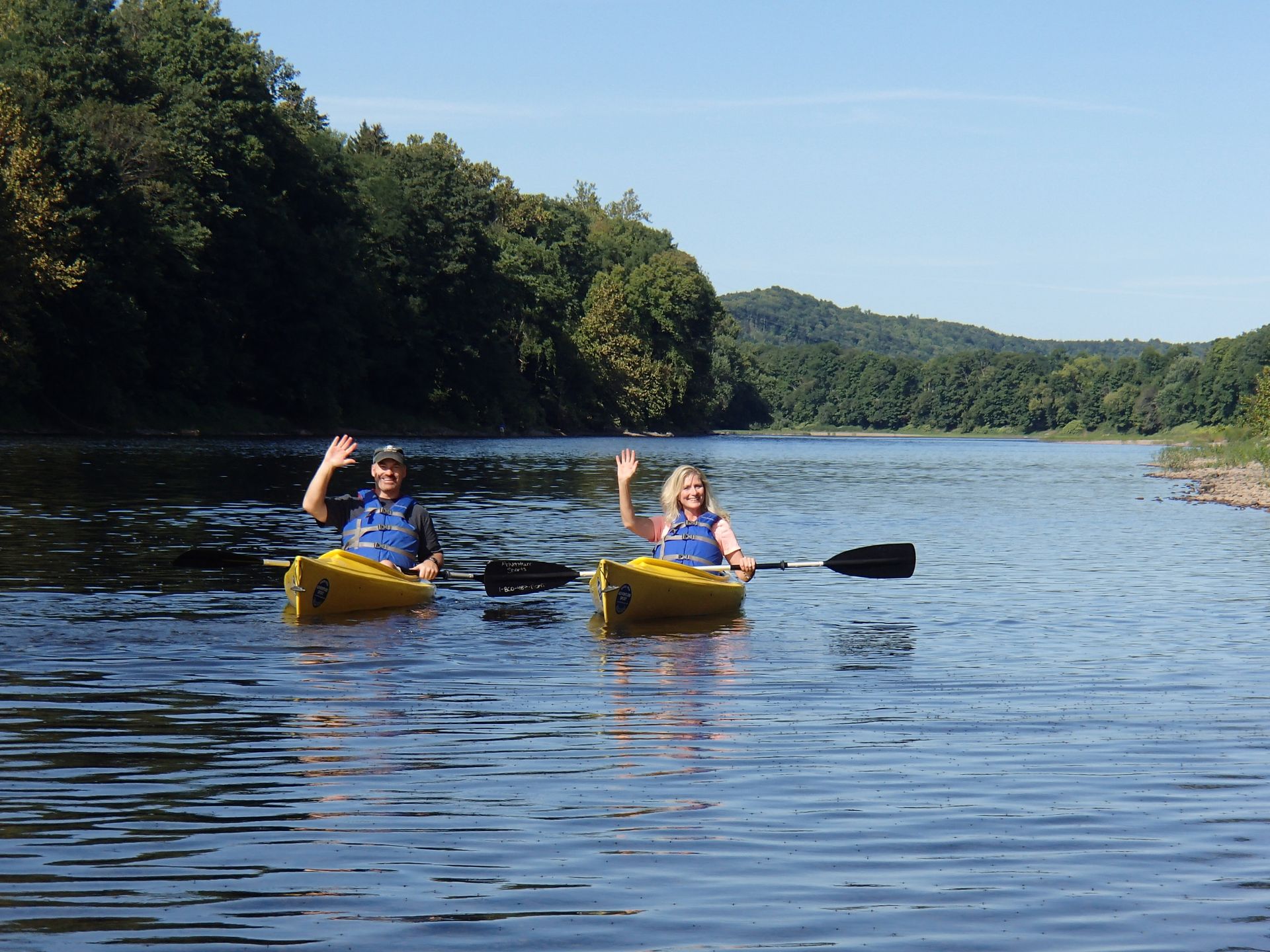 A man and a woman are rowing adventure sports kayaks on the Delaware River