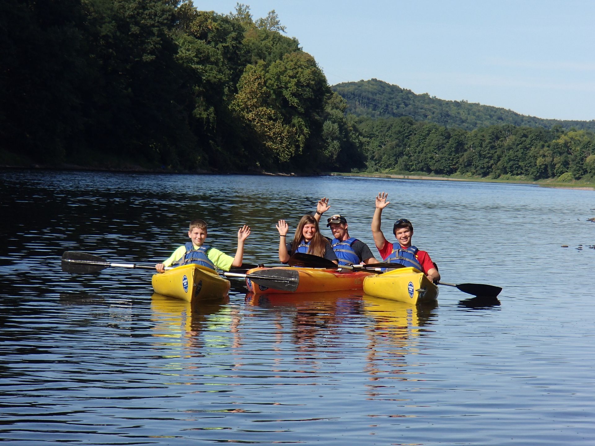 A group of people are rowing adventure sports kayaks on a lake