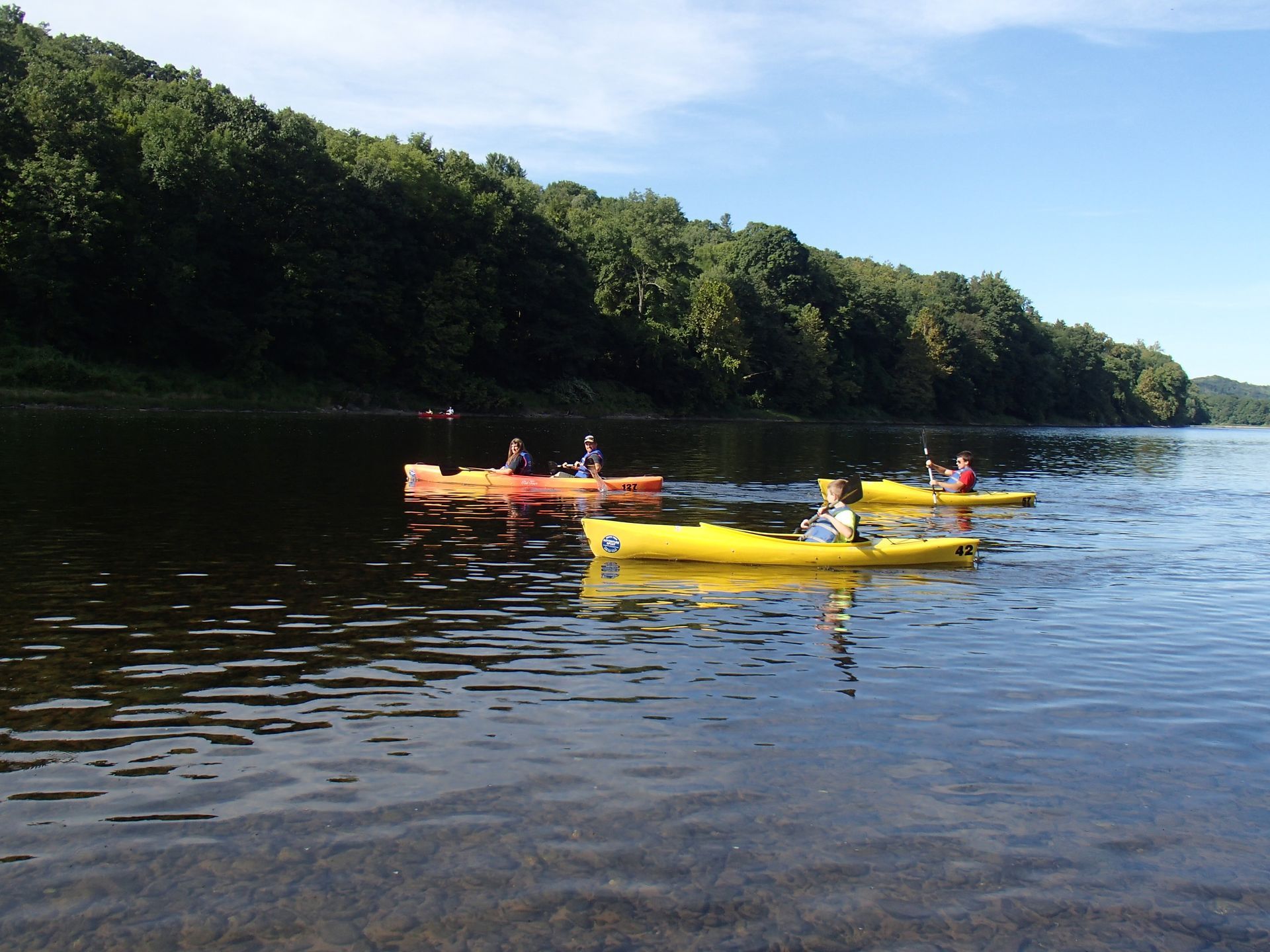 A group of people in yellow adventure sports kayaks on a lake