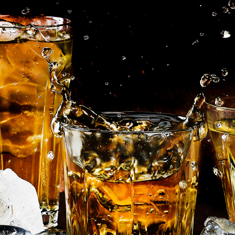 A glass of whiskey with ice is being poured into another glass on Adventure Sports website