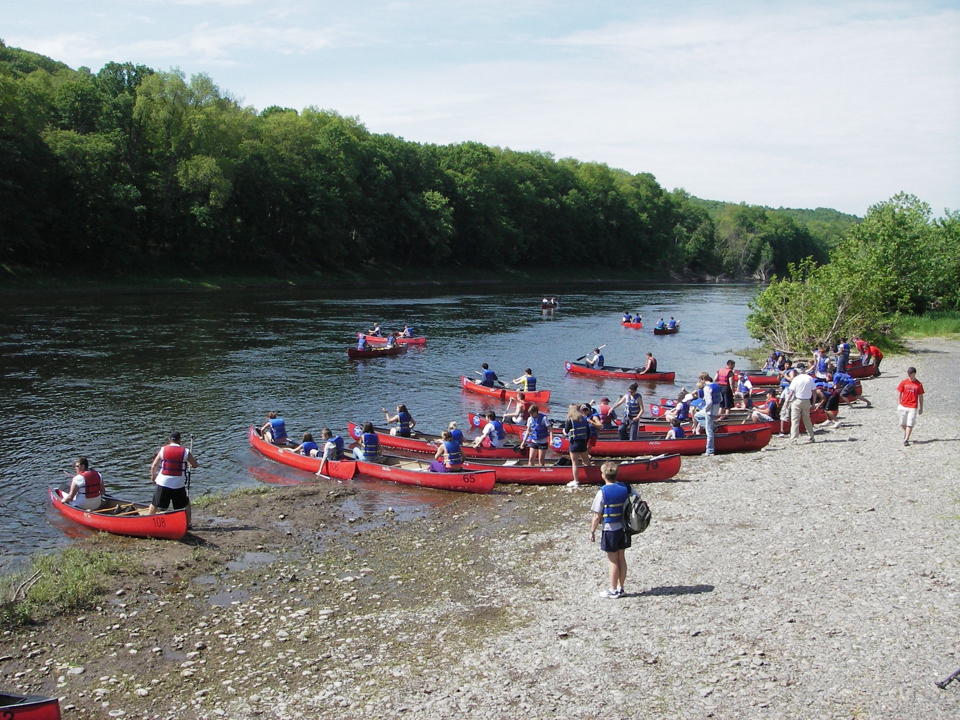 A group of people in red adventure sports canoes on a river