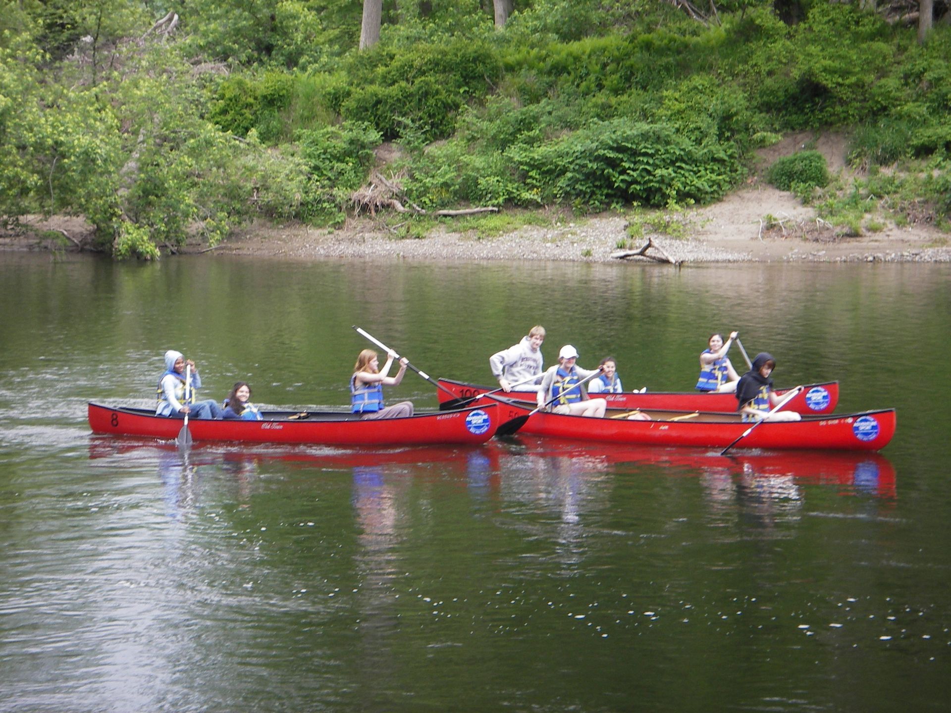 A group of people in red adventure sports canoes on a lake