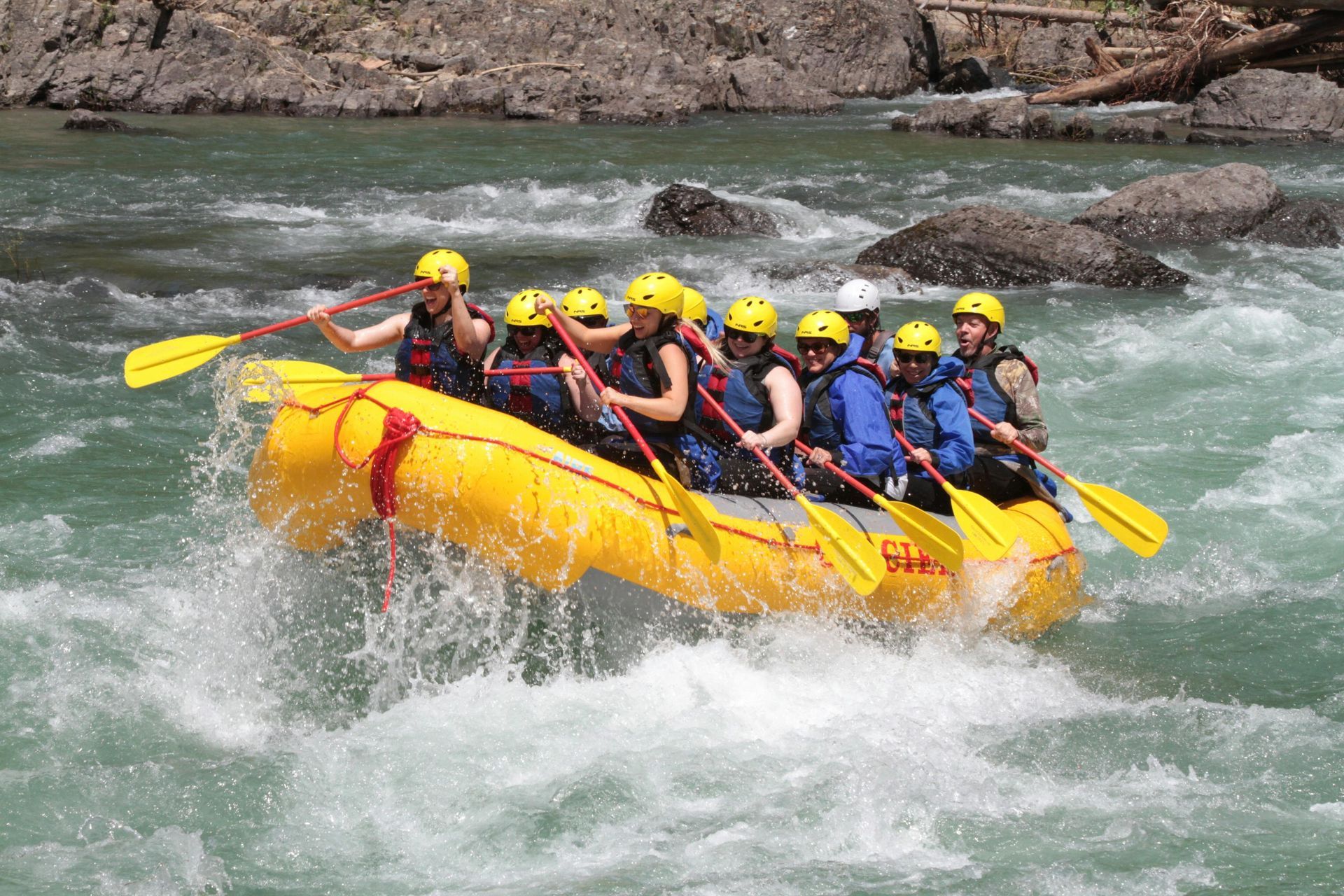 A group of people are rafting down a river in a yellow raft.