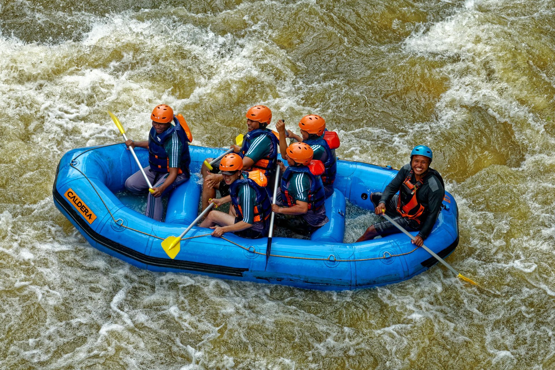 A group of people are rafting down a river in a blue raft.