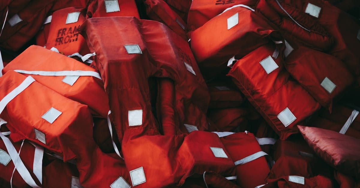 A pile of red life jackets are stacked on top of each other.