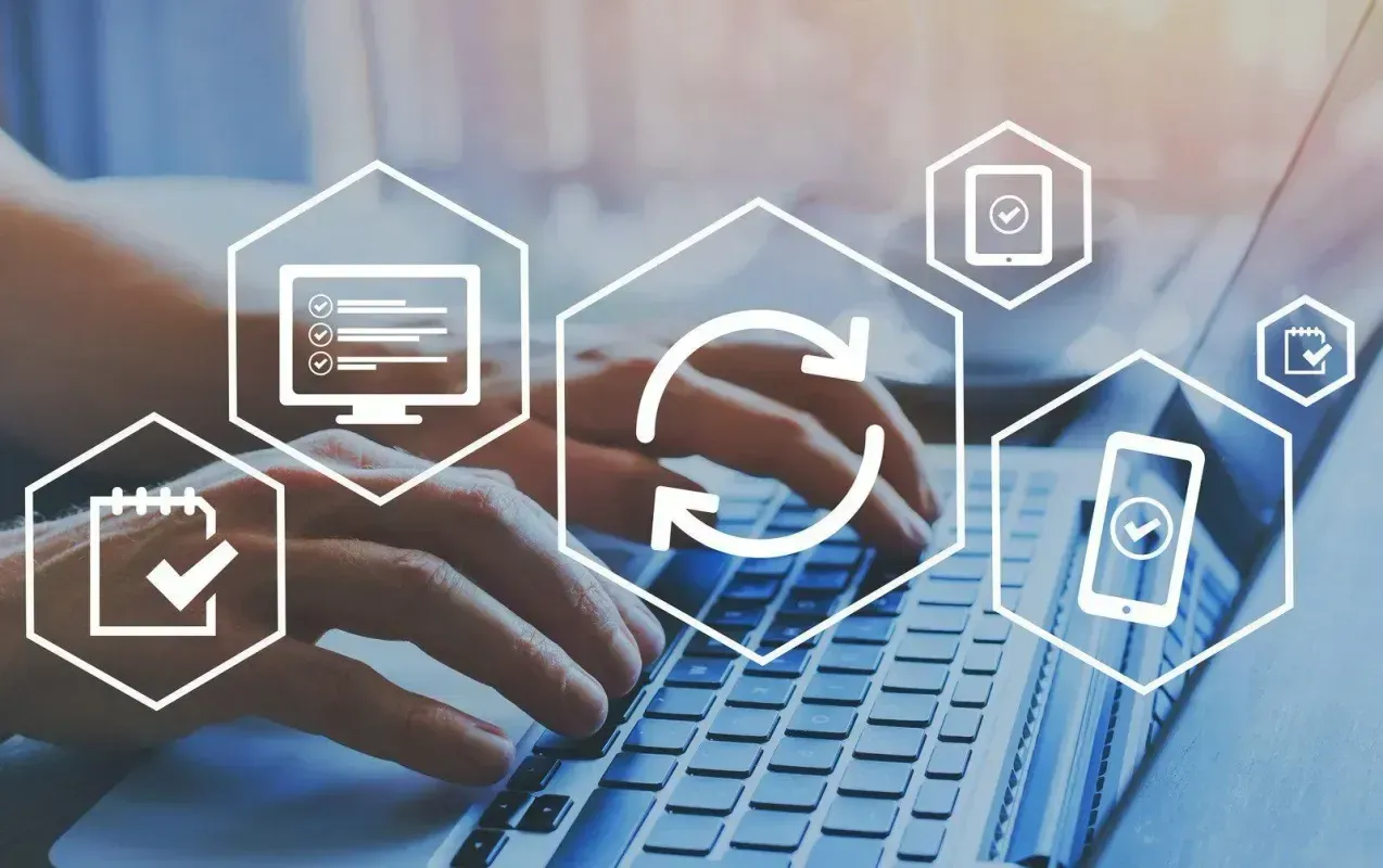 Hands typing on a laptop with overlaying hexagonal icons representing digital tasks and synchronization