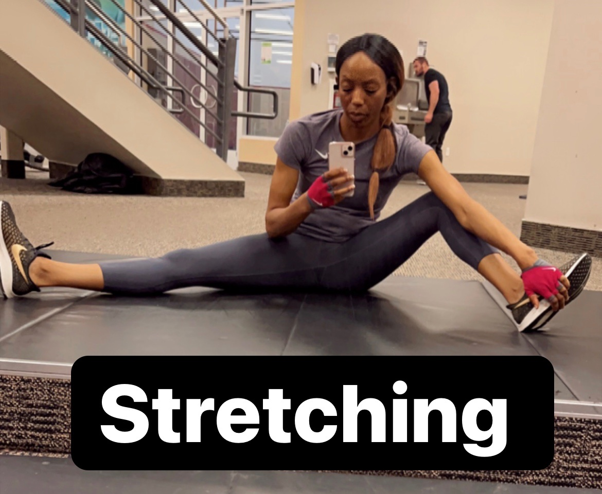 A woman is sitting on the floor stretching her legs
