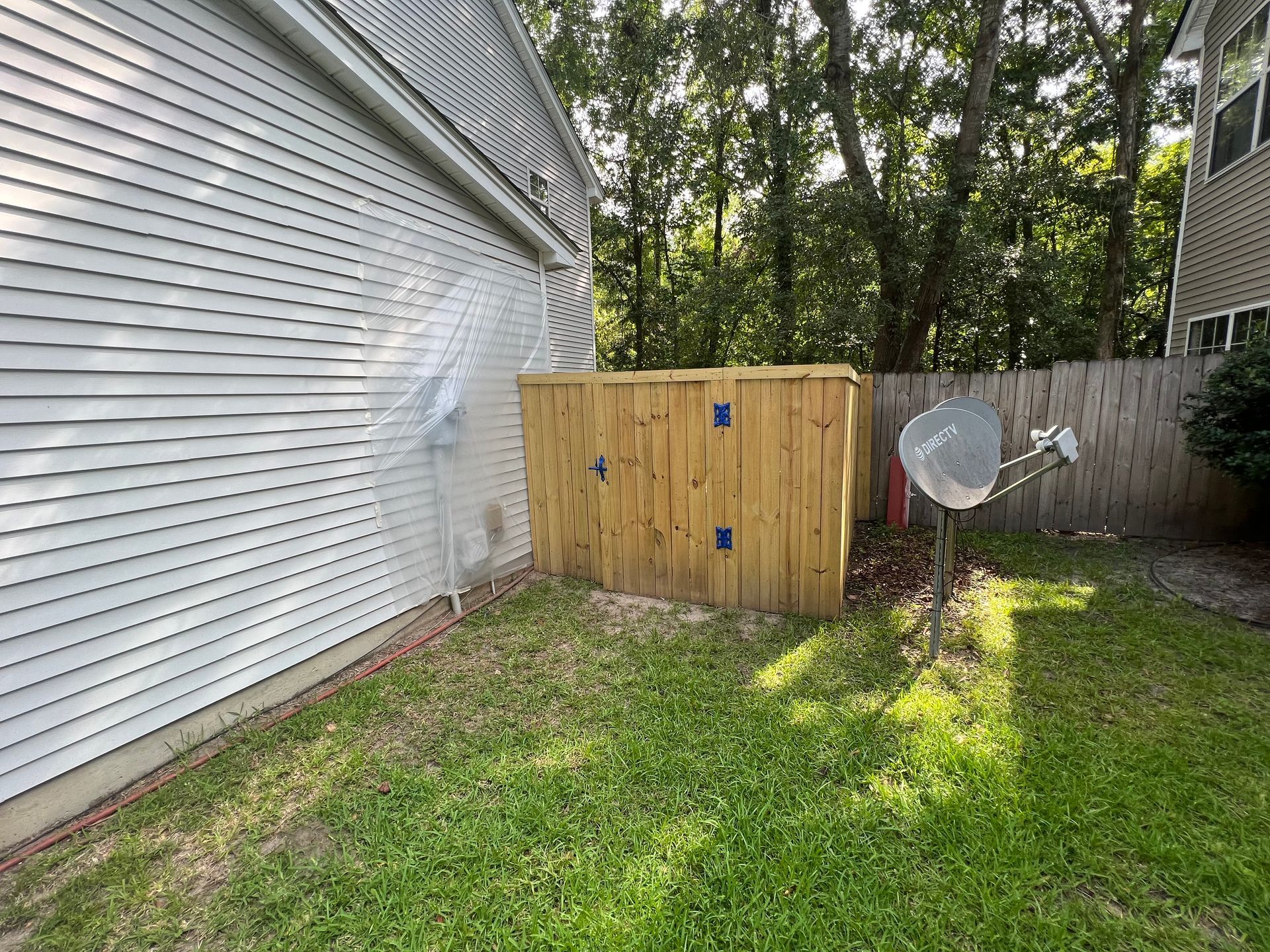 A wooden fence with a satellite dish in the backyard of a house.