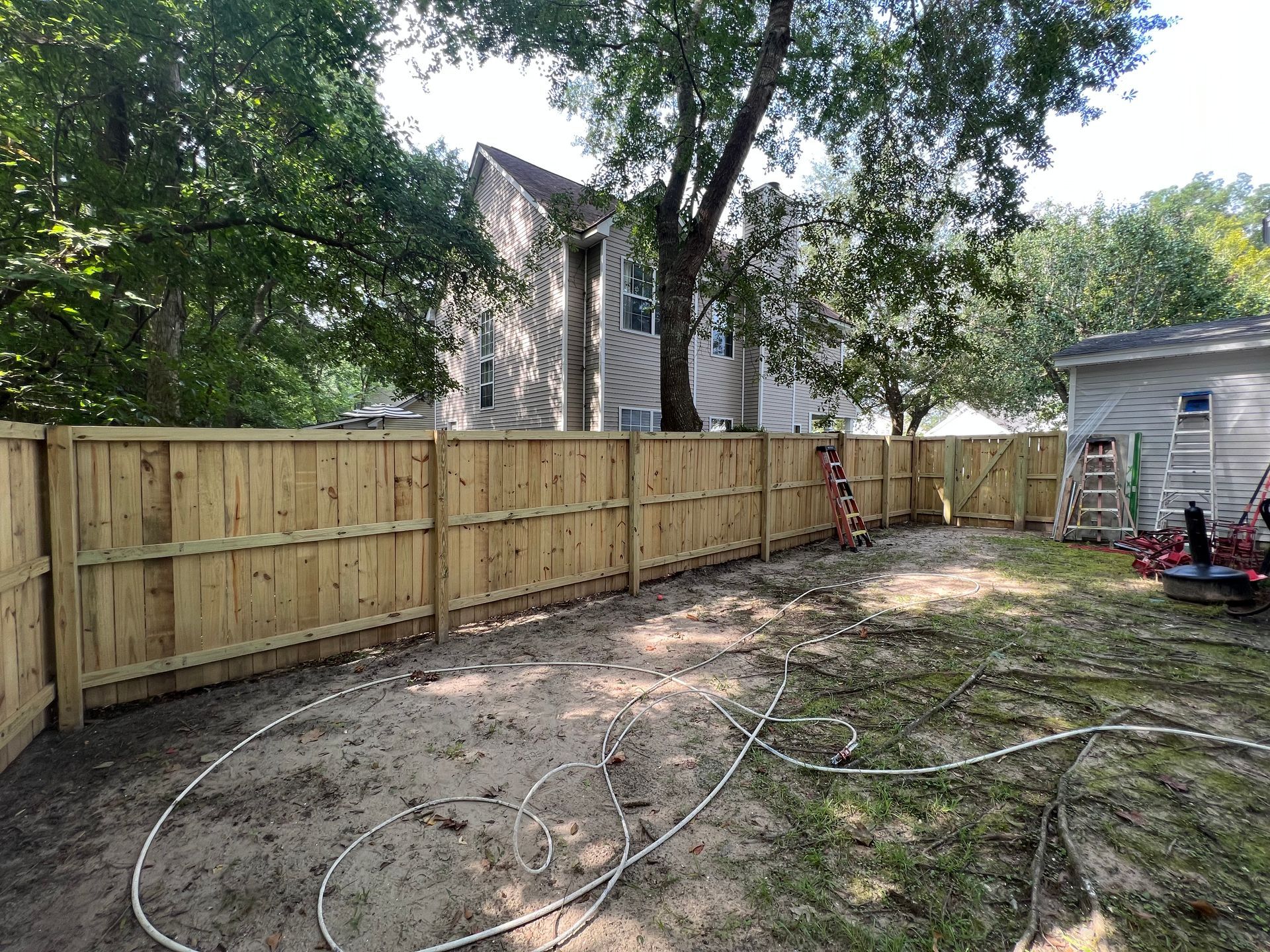 A wooden fence is being built in the backyard of a house.