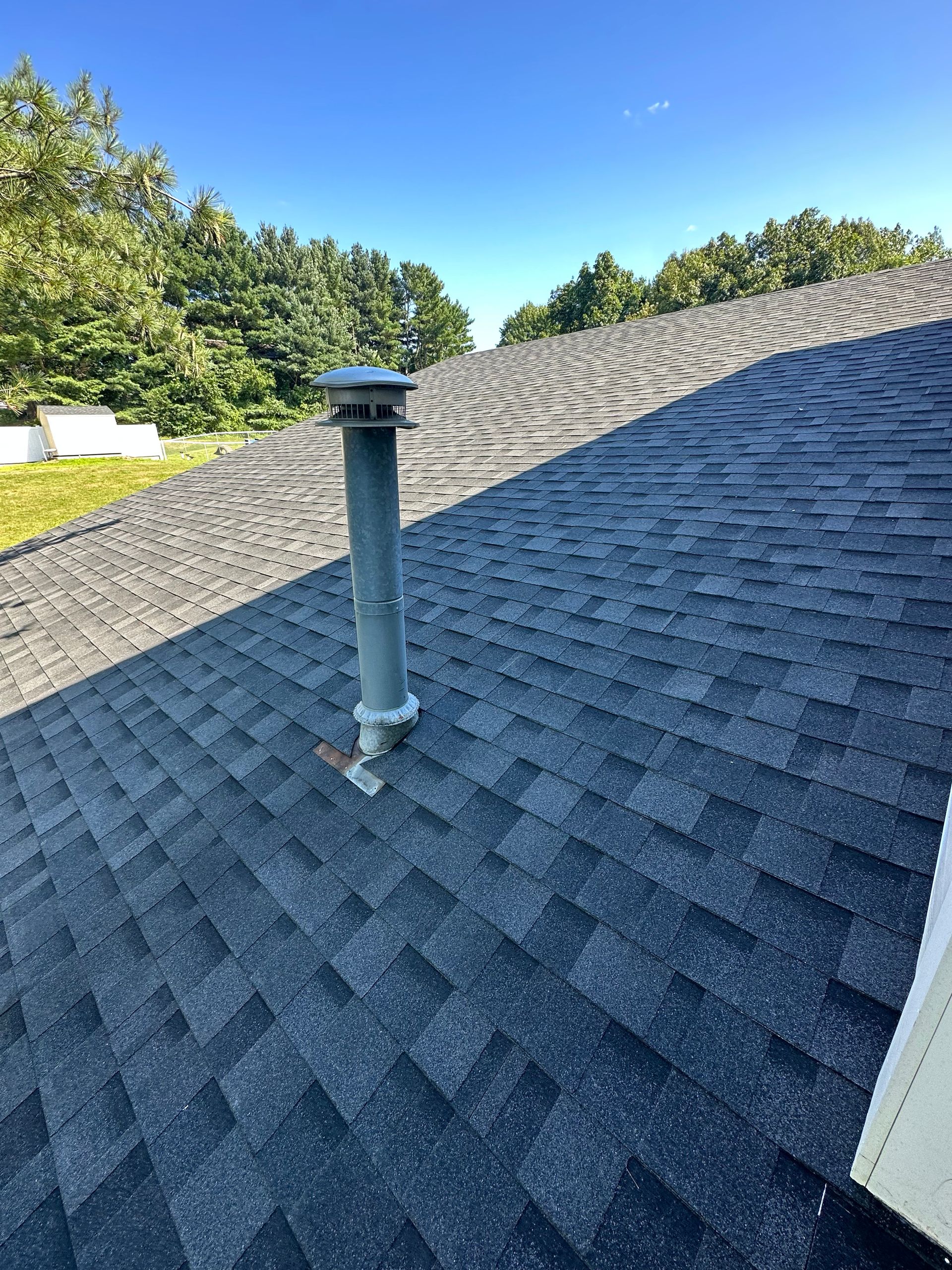 A roof with a chimney on it and a blue sky in the background.