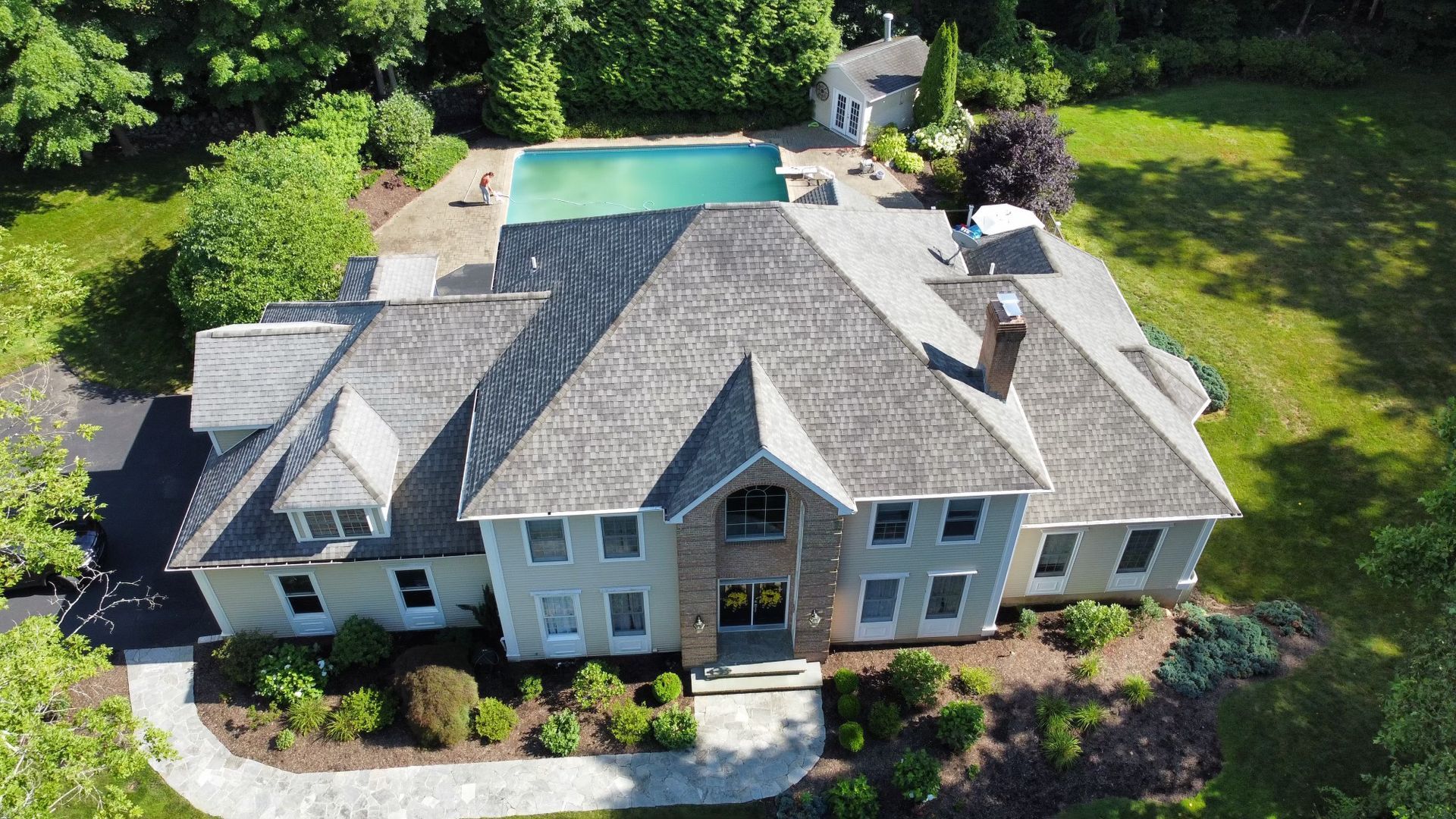 An aerial view of a large house with a pool in the backyard.