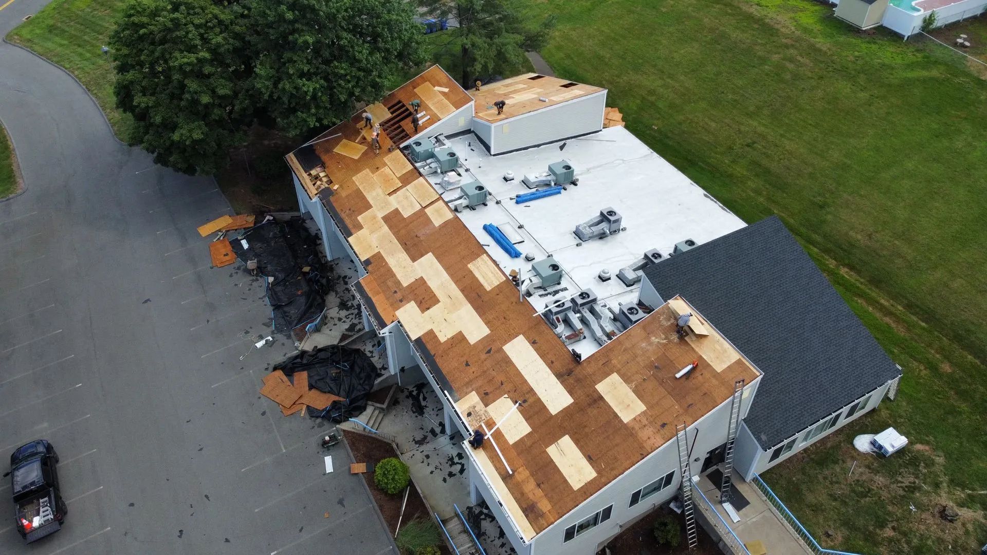 Aerial view of a building with a partially damaged roof; brown and white roof sections.