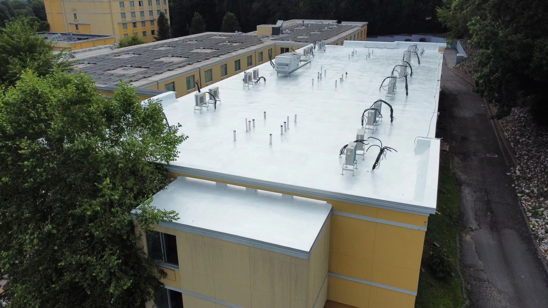 Yellow building with a white, reflective roof and various mechanical units.