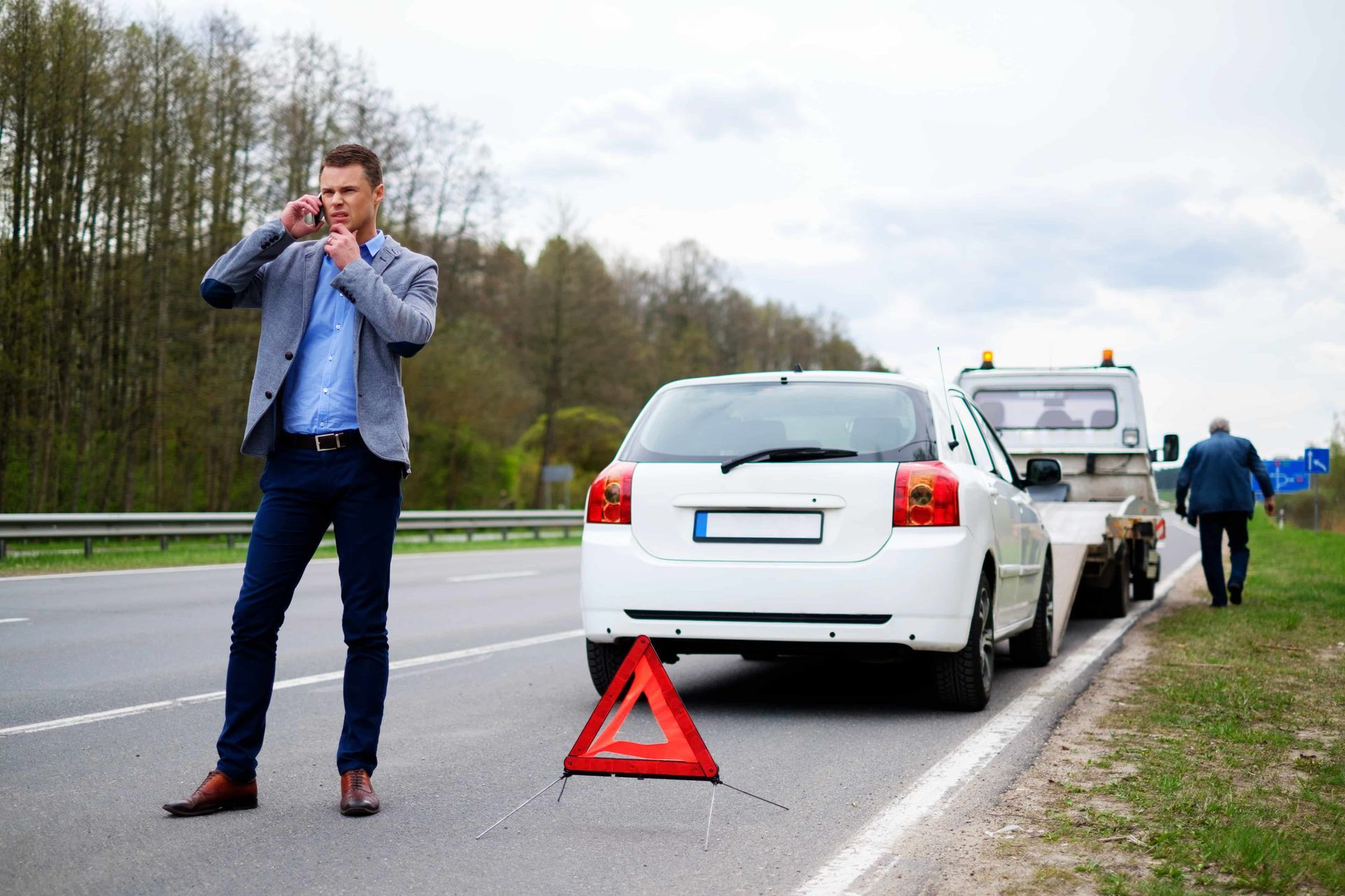 Man on the phone making a call after vehicle breakdown on the side of the road