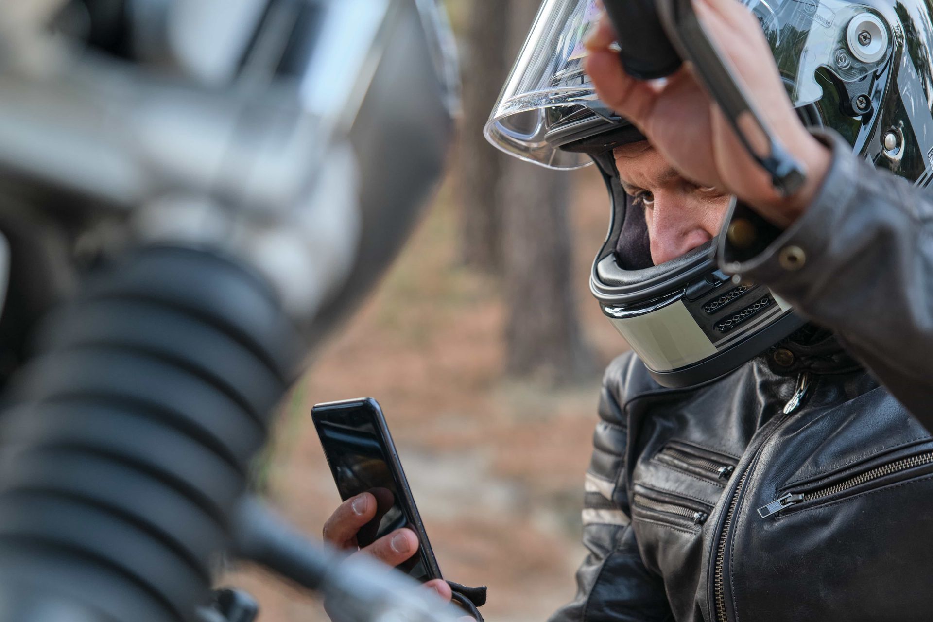 man with motorcycle helmet scrolling phone