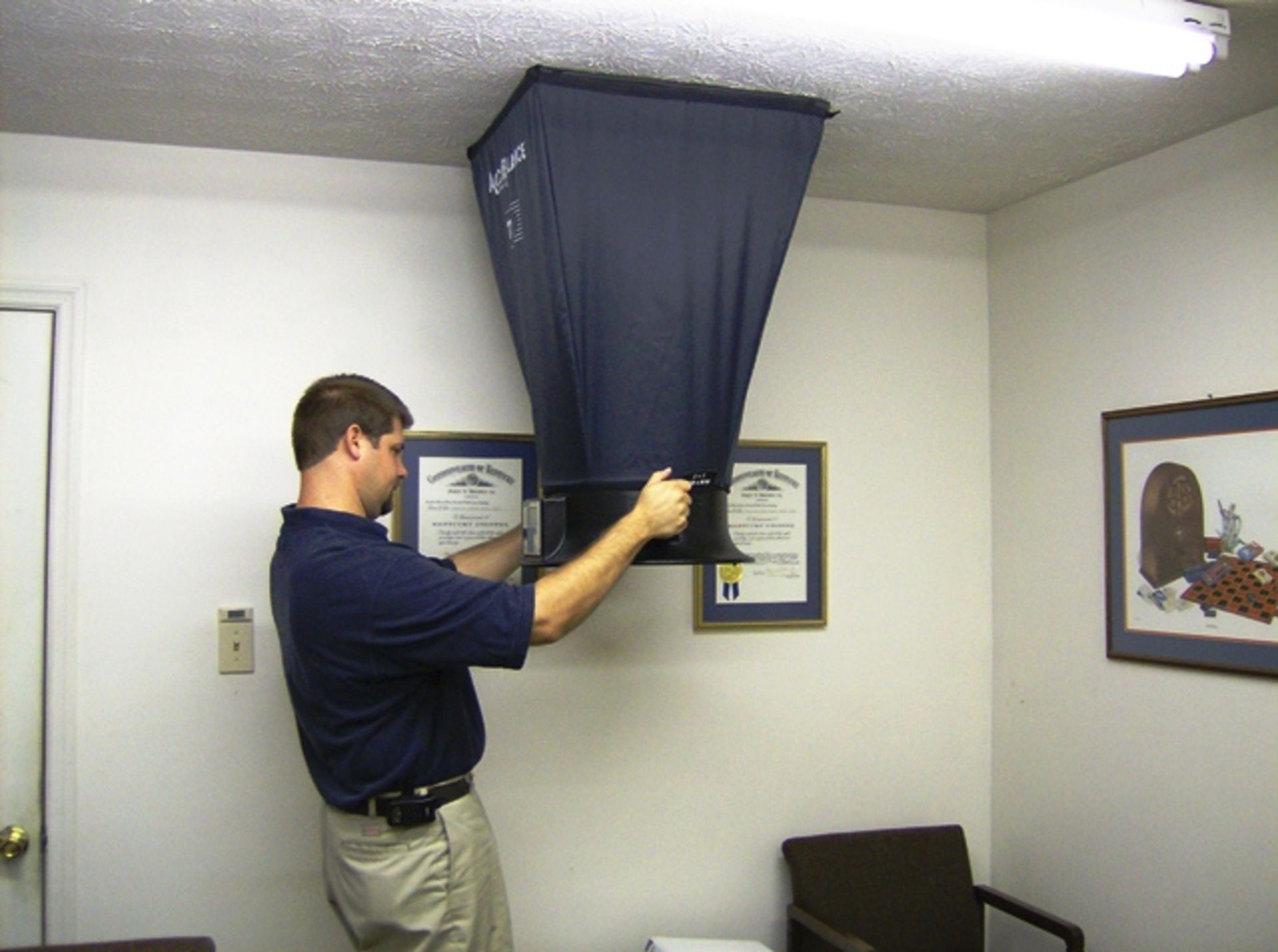 A man in a blue shirt is adjusting a ceiling fan