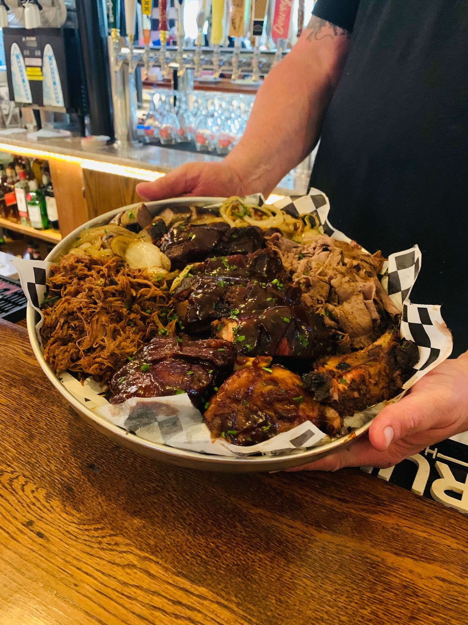 A person is holding a plate of food on a wooden table.