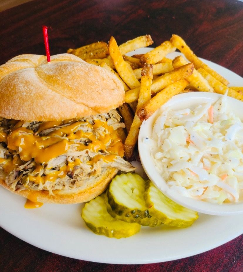 A pulled pork sandwich with french fries and coleslaw on a plate