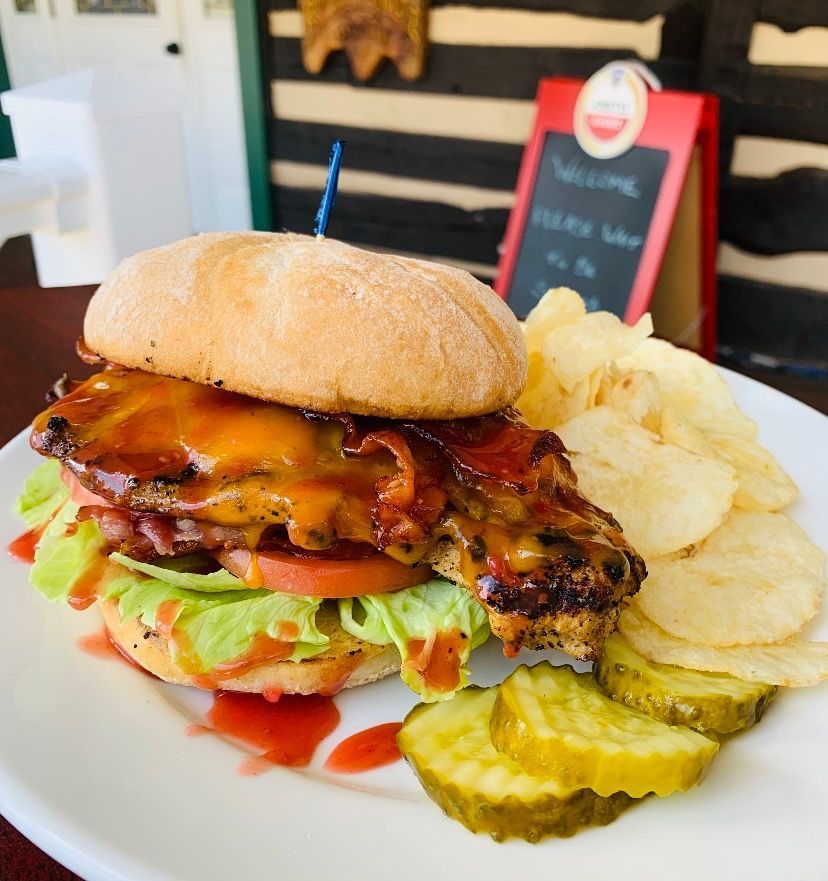 A white plate topped with a chicken sandwich and chips