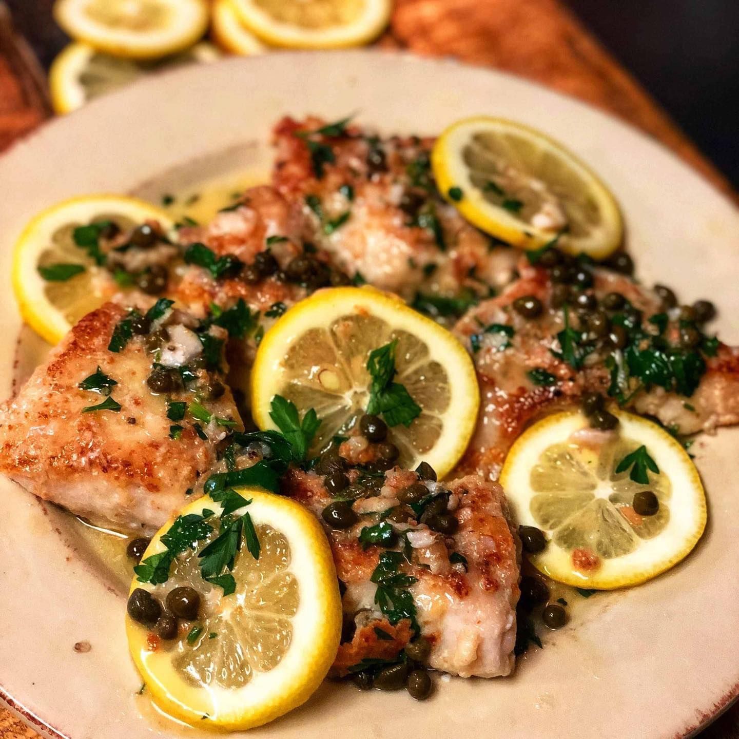 A plate of food with lemon slices and capers on it
