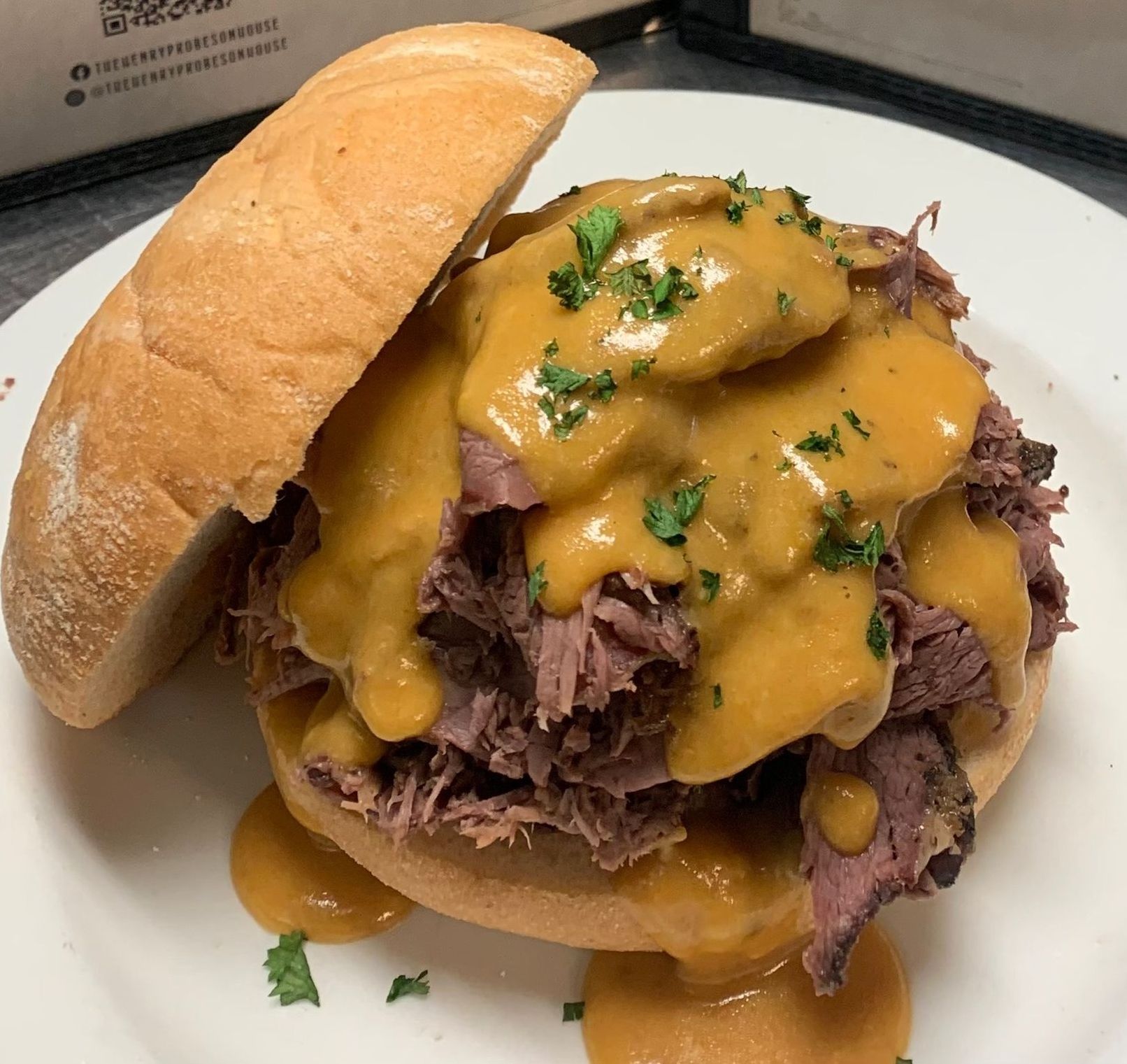 A sandwich with meat and cheese on a bun on a white plate