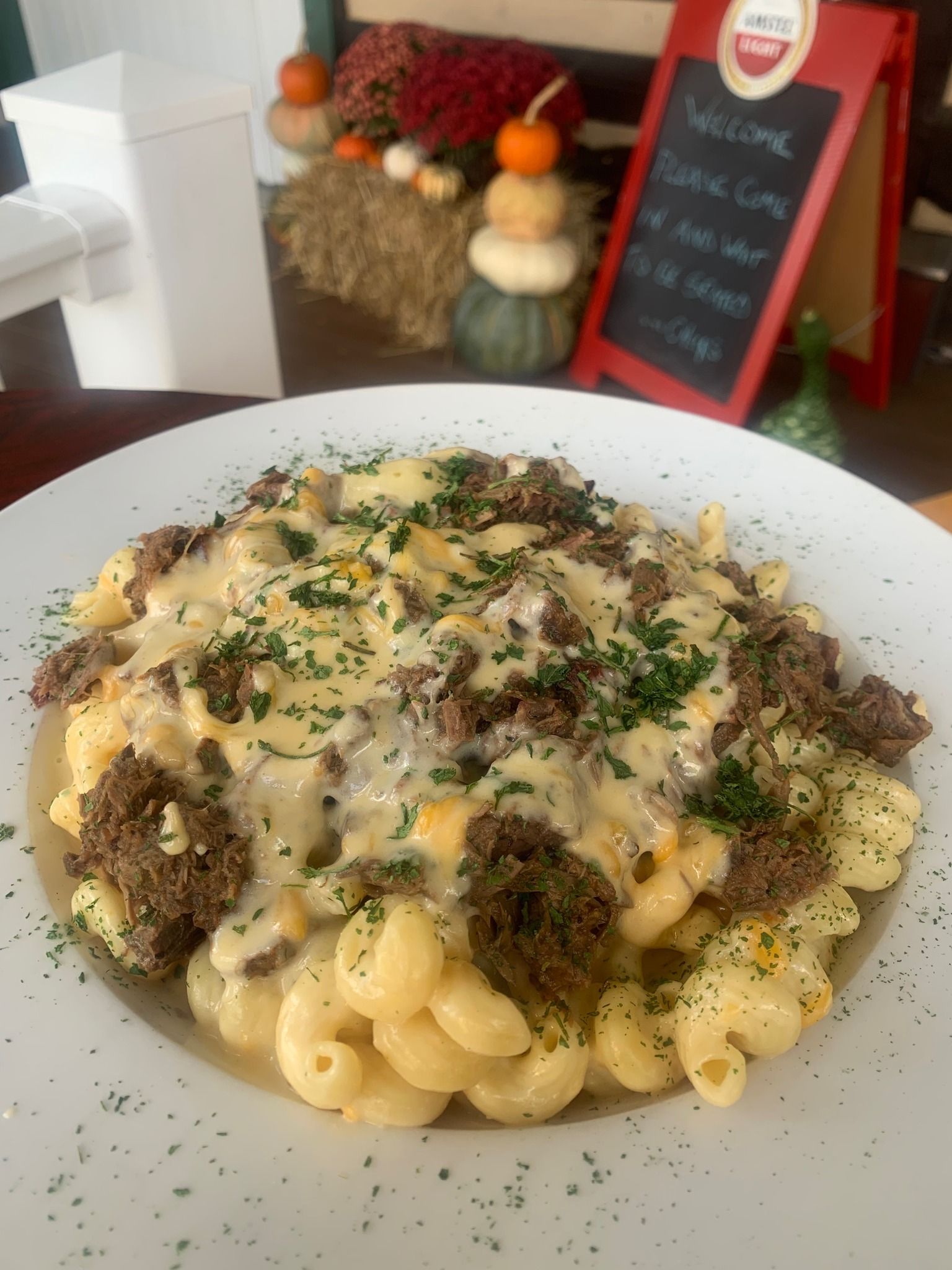 A plate of macaroni and cheese with meat and cheese on a table.