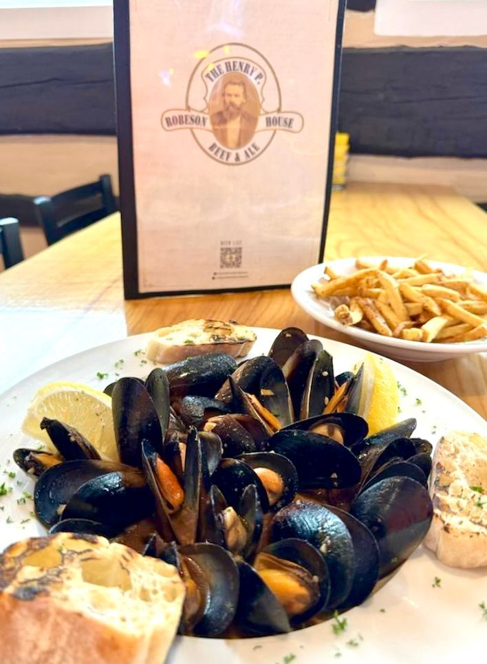 A plate of mussels and french fries on a table next to a menu.