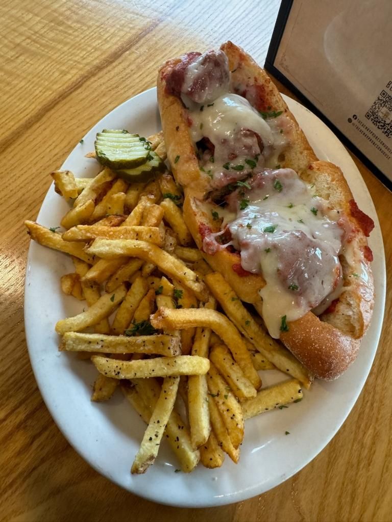 A plate of food with french fries and a sub sandwich on a table.