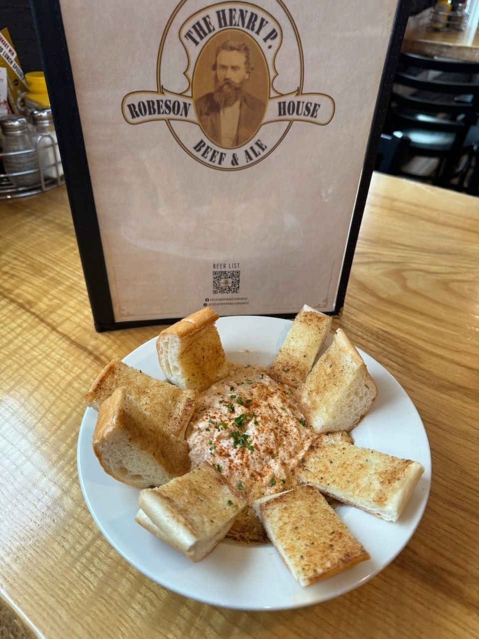 A plate of food with garlic bread next to a menu for the henry p. house