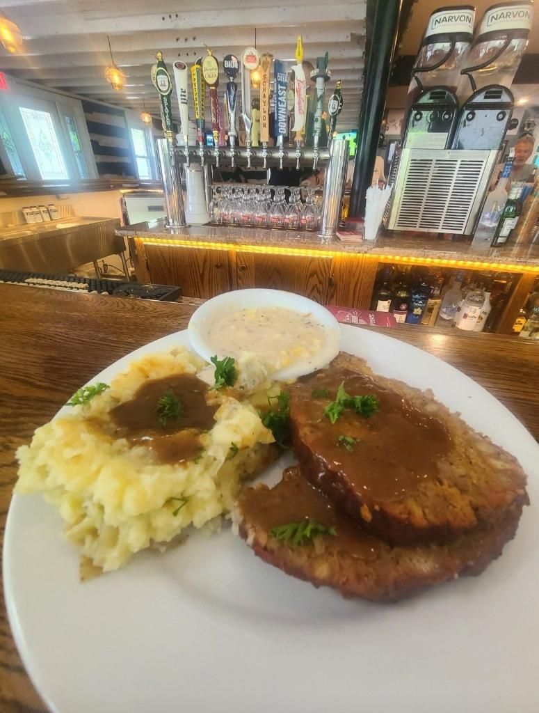 A plate of food with meat and mashed potatoes on a table in a restaurant.