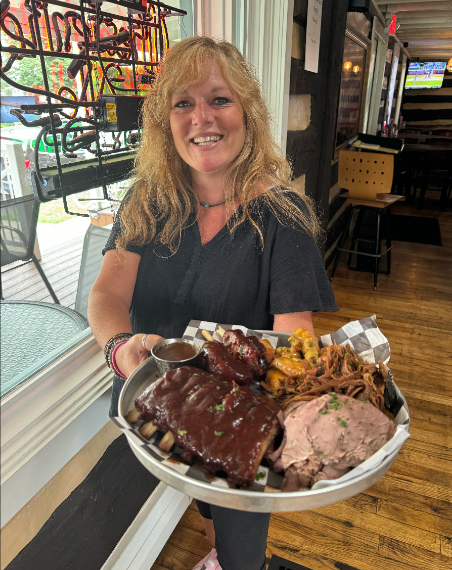 A woman is holding a tray of food in a restaurant.