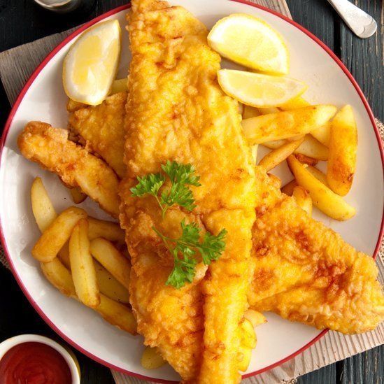 A white plate topped with fried fish and french fries