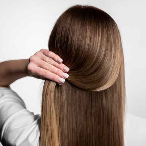 A woman is holding her hair in a ponytail.