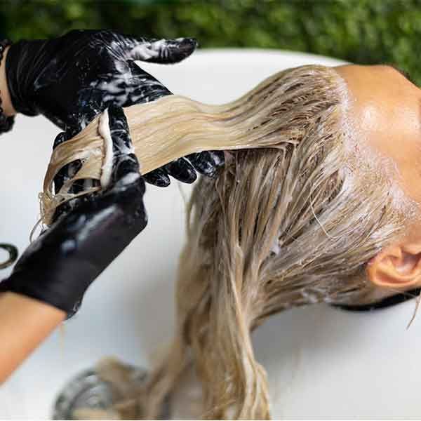 A woman is getting her hair washed in a sink.