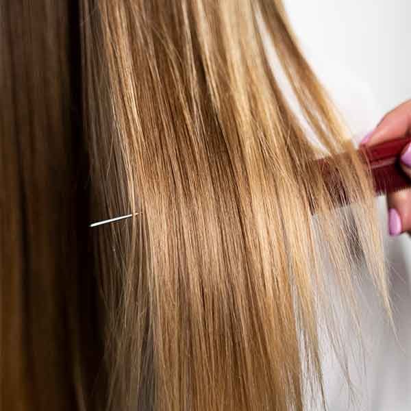 A woman is brushing her long blonde hair with a comb.