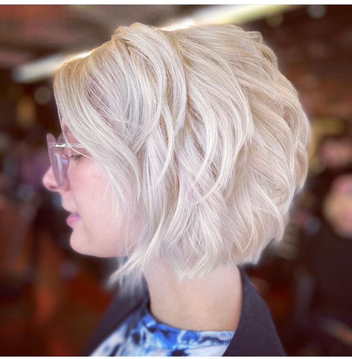 A woman with blonde hair wearing glasses and a blue shirt