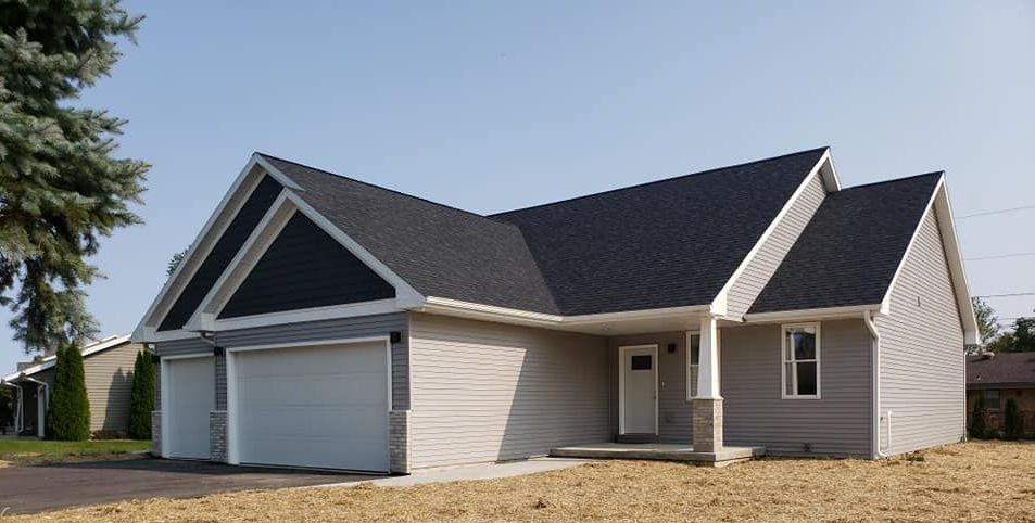 A house with a black roof and two garage doors