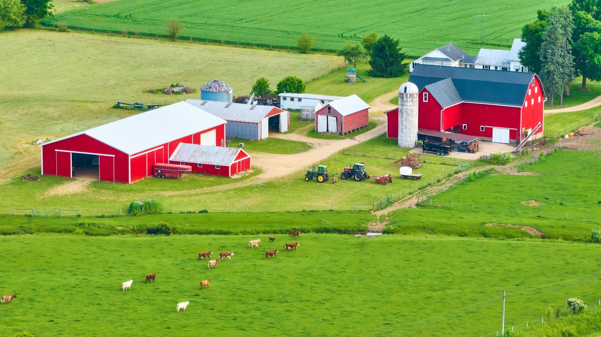 An aerial view of a farm with a red barn and a white barn