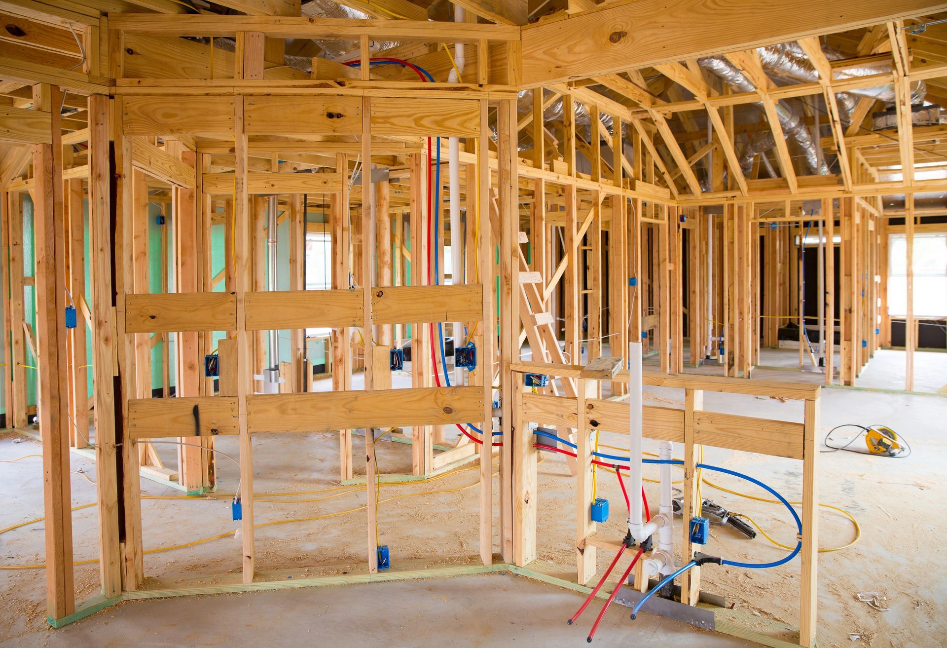 The inside of a house under construction with wooden beams and pipes.