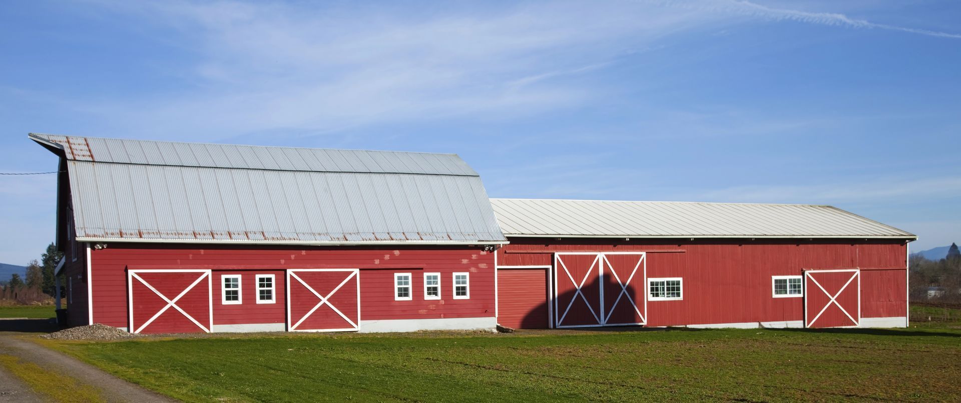 A red barn with a white roof is in a grassy field