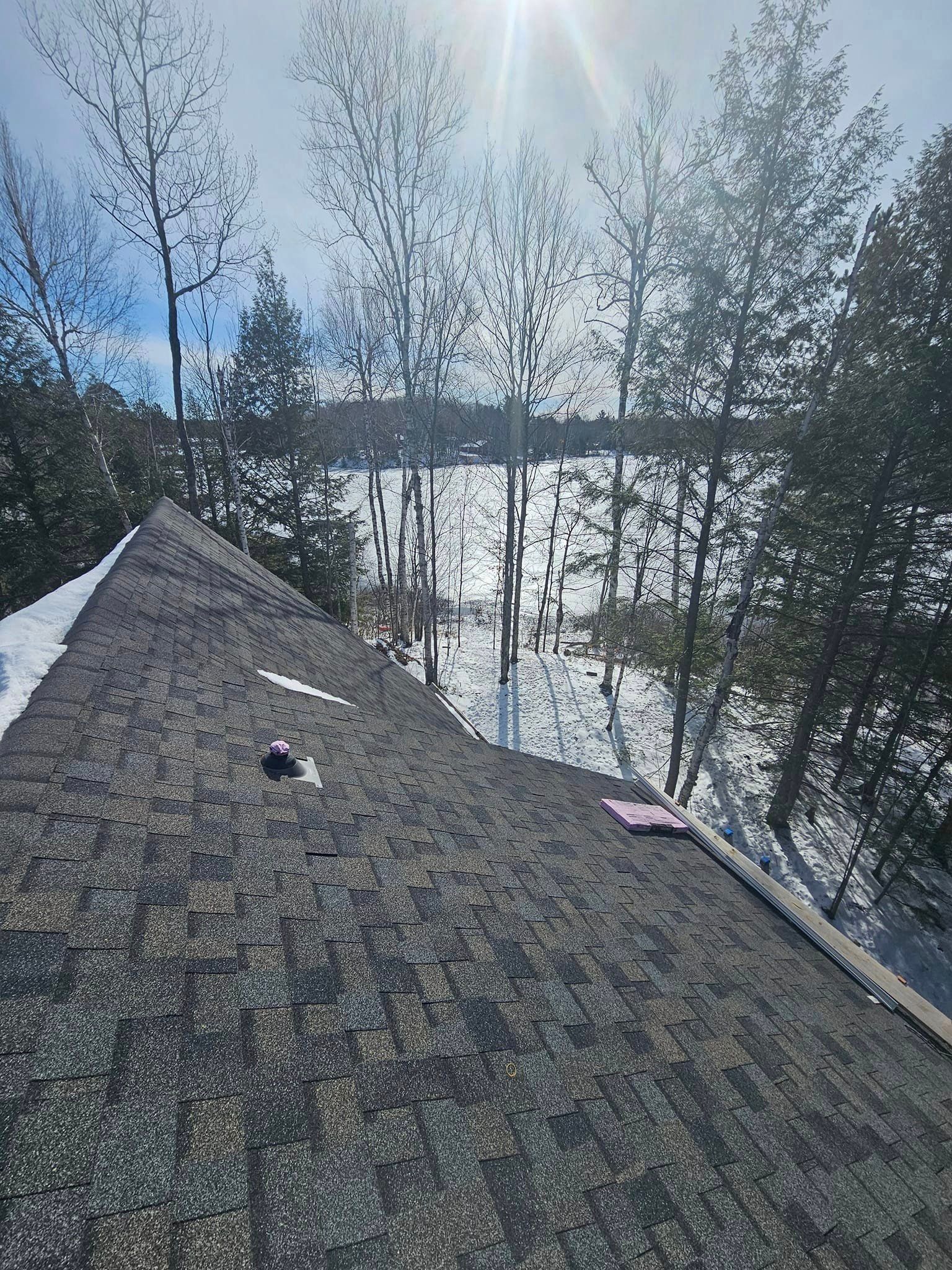 A roof with a view of a lake and trees in the background.