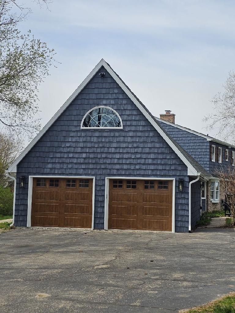 A blue house with two garage doors and a window