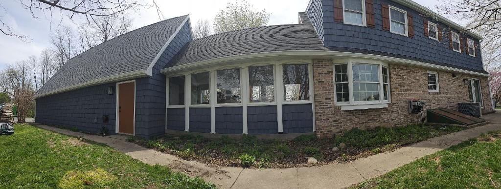 A large brick house with a blue roof and a large porch.