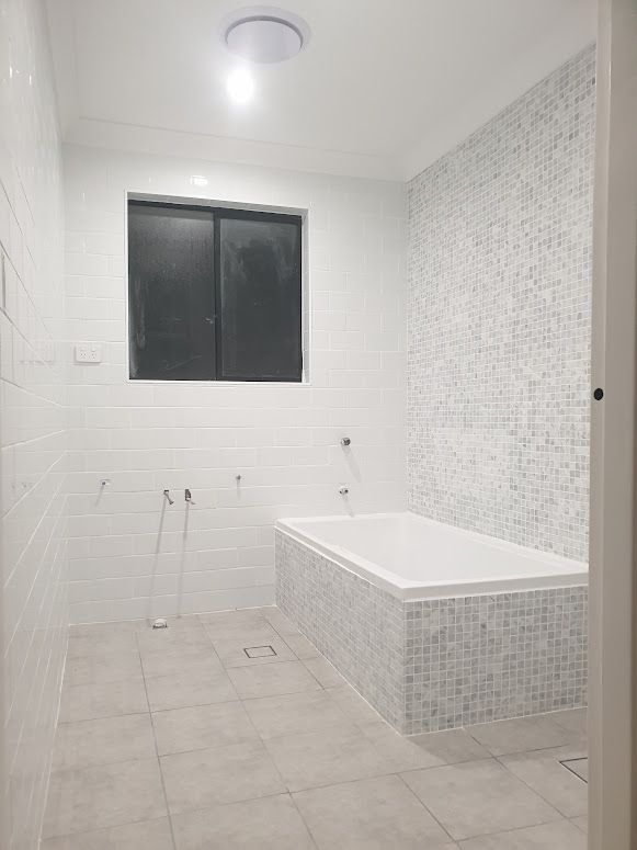 A bathroom with a bathtub and a window.