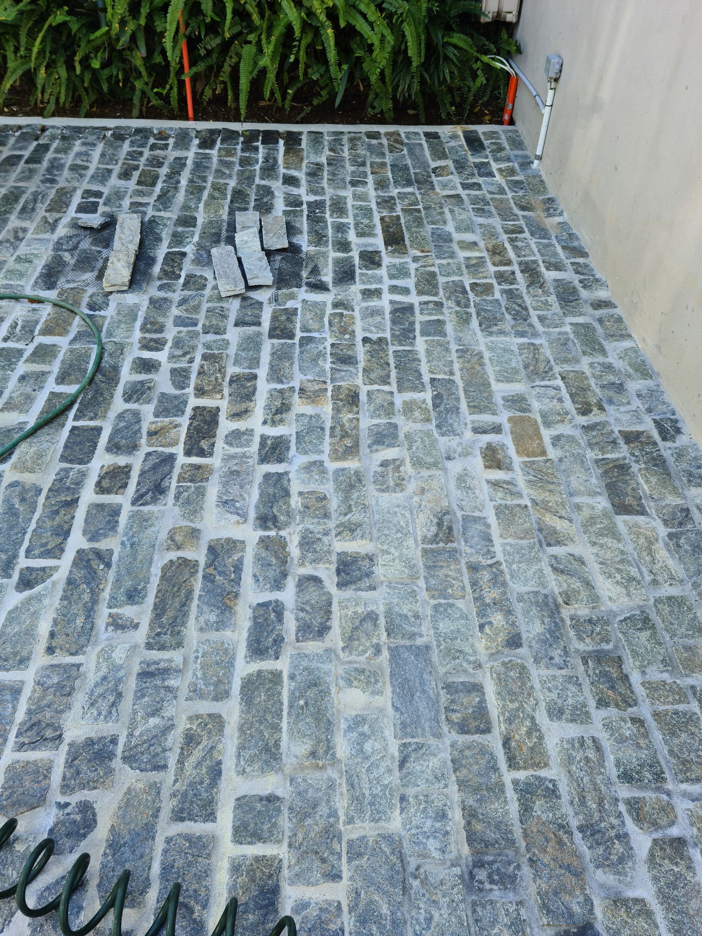 A hose is laying on a cobblestone driveway — South Coast Flooring in Berkeley, NSW